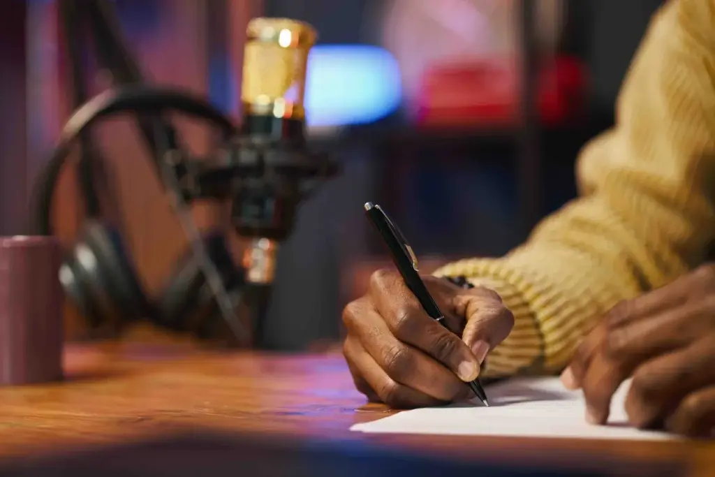 A writer marking notes by hand at a home studio desk